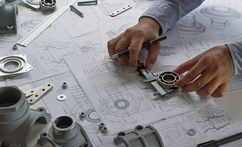 Engineer technician designing drawings mechanical parts engineering Engine.manufacturing factory Industry Industrial work project blueprints measuring bearings caliper tools