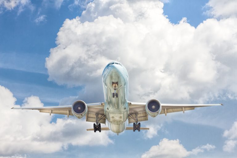 A plane in flight with white clouds in the sky.